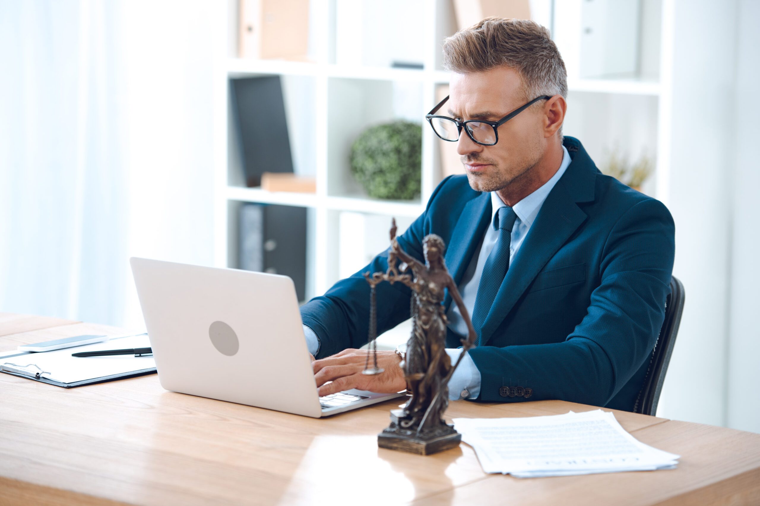 handsome lawyer in eyeglasses using laptop at workplace handsome lawyer in eyeglasses using laptop at workplace